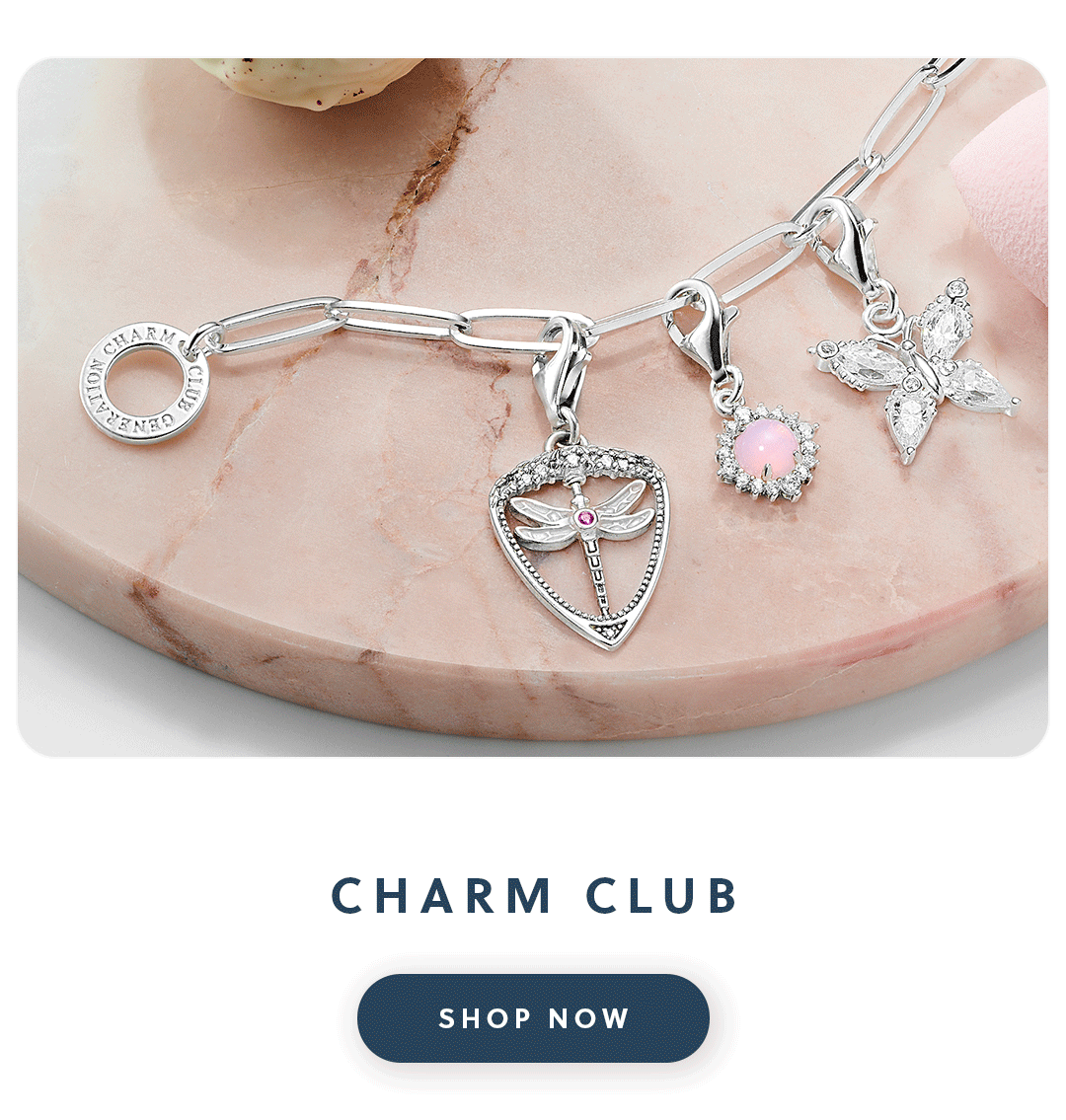 A close up of a Thomas Sabo charm bracelet with three charms with text charm club shop now