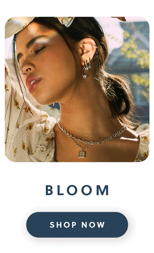 A close up of a woman wearing Daisy London Bloom jewellery with text bloom shop now