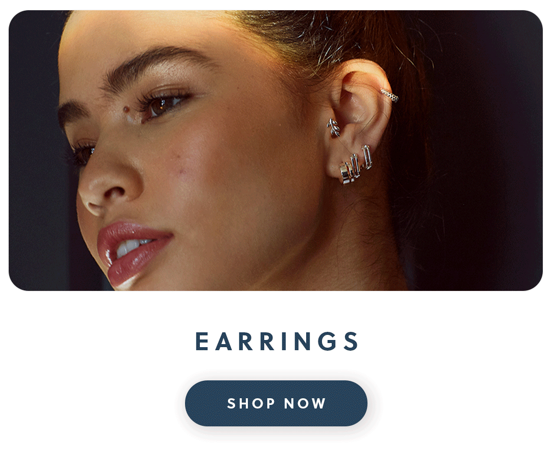 A close up of a woman wearing silver Daisy London earrings with text earrings shop now