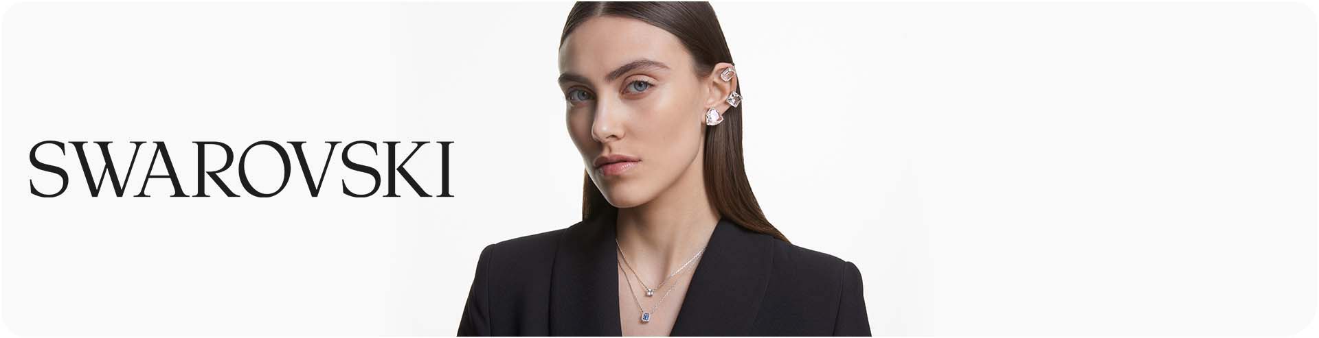 Woman wearing a collection of silver Swarovski jewellery including earrings and necklaces with the Swarovski logo
